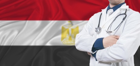 Egypt healthcare concept. Male doctor on Egypt flag. Doctor with crossed arms on Egypt flag