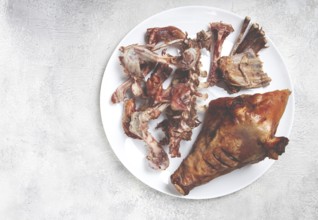 Roast pork head, with remnants of bones and meat, on a white platter, no people, close-up