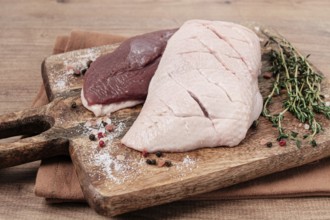 Fresh raw duck breasts, on a wooden chopping board, with herbs and spices, no people