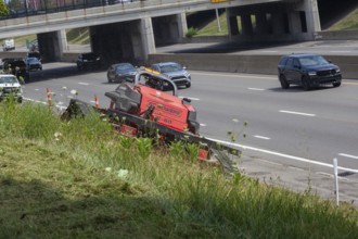 Harper Woods, Michigan - Remote-control mowers are cutting the grass and weeds along Interstate 94