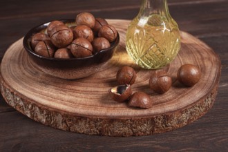Bottle of macadamia oil, on a wooden board, with macadamia nuts, wooden background, selective