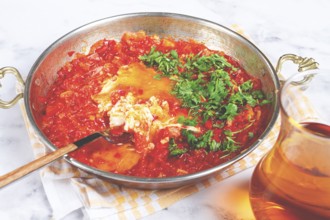 Traditional Turkish dish, scrambled eggs with tomatoes, Menemen, with herbs, in a frying pan,