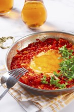 Traditional Turkish dish, scrambled eggs with tomatoes, Menemen, with herbs, in a frying pan,