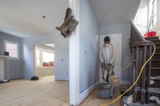 Detroit, Michigan - Workers sand a floor as they remodel a house in the Morningside neighborhood.