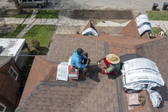Detroit, Michigan - Workers take a break while re-roofing a house they are remodeling in the