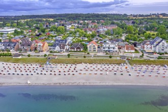 Aerial view over sandy beach with roofed wicker beach chairs and seaside resort Haffkrug along the