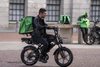 Bicycle traffic in Groningen, Uber Eats, courier driver with e-bike in moped style, fatbike,