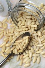 Pine nuts in glass container and spoon, Pinus pinea