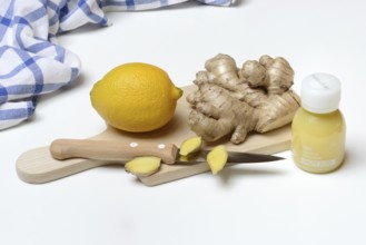 Ginger root and lemon on cutting board with knife, ginger shot