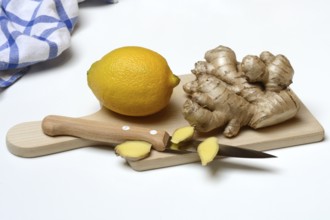 Ginger root and lemon on kitchen board with knife, ginger slices, Zingiber officinale