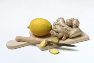 Ginger root and lemon on cutting board with knife, ginger slices, Zingiber officinale