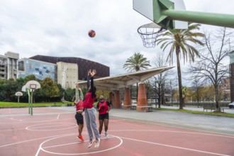 Diverse group of friends enjoying a casual game of street basketball on a red court, actively