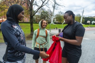 Three diverse friends, including two women wearing sportswear, are cheerfully gathering their gear