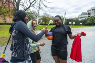 Three diverse friendswoman in hijab, man with curly hair, and woman holding a colorful
