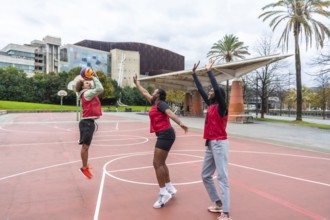 Group of diverse young athletes enjoying a spirited game of basketball outdoors, actively involved