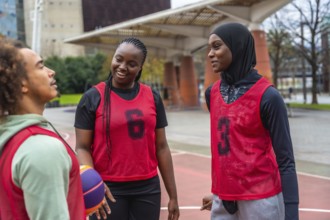 Group of diverse young athletes, including men and women, wearing red training bibs and a hijab,