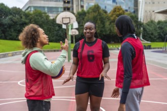 Diverse young adults on an urban basketball court talking strategy and bonding over streetball,