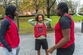 Group of diverse young adults wearing red training bibs, including a woman in a hijab, standing in