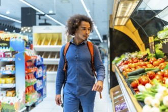 Man with curly hair and backpack browsing vibrant fresh fruits and vegetables in a bright
