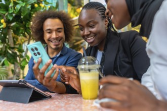 Diverse friends are happily socializing at a cafe, using a smartphone to view and share content,