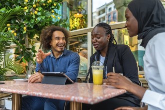 Diverse young professionals and friends gathered in a relaxed cafe, laughing, sharing ideas and