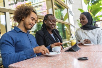 Diverse group of young adult friends enjoying a casual meeting in a modern cafe, sharing