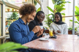 Diverse group of friends and coworkers gathered in a modern cafe, smiling and laughing over coffee