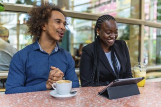 Two diverse business professionals are meeting in a relaxed cafe environment, discussing ideas and