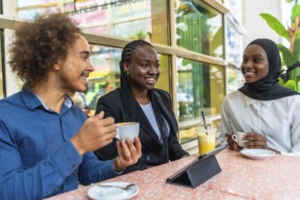 Diverse group of young adult friends smiling and engaging in conversation while sitting at a table