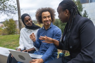 Diverse colleagues discussing and brainstorming ideas while working on a laptop together,