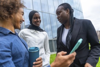 Group of multi ethnic colleagues engaging in a friendly conversation outside a modern office