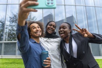 Three diverse friends smiling and laughing while taking a group selfie with a smartphone,