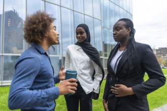 Diverse business professionals standing outdoors, engaging in an informal discussion during a
