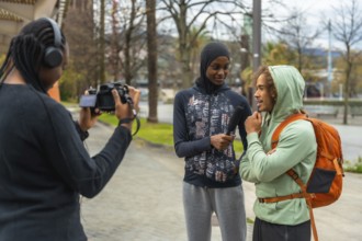 Diverse young content creators conducting a street interview with a gen z man in an urban public