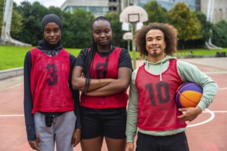 Diverse group of young adult basketball players standing on an outdoor court, proudly wearing
