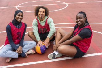 Diverse young friends wearing sport jerseys and a hijab, smiling while sitting together on an