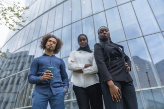 Diverse business team of young professionals standing together with confident expressions against a