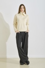 A young woman stands confidently in a stylish, cozy winter outfit that emphasizes convenience and