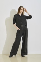 A stylish woman stands confidently in a trendy outfit, combining comfort and practicality