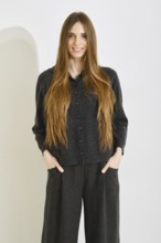 Smiling woman poses in a comfortable black outfit featuring a soft button-up top and loose pants on
