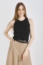 A young woman showcases a trendy black sleeveless top paired with wide-legged beige pants. This