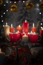 Red and white candles with cups on a table against a Christmas decorated background