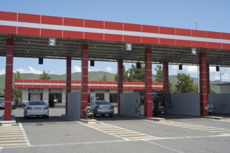 Gas station with red roof, numbered passages and parked cars, gas filling station, Sewan,