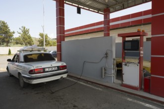 White car connected to red gas station pump under a canopy, gas filling station, Sewan, Gegharkunik