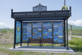 Bus stop with information posters surrounded by rural landscape under blue sky, bus stop at Lake