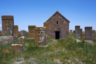 Church surrounded by ancient tombstones in a green setting under a blue sky, crossstones,