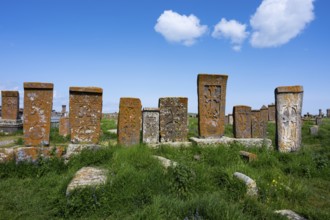 Old crossstones on a green field under a blue sky with clouds, crossstones, khachkars, world's