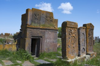 Decorated mausoleum and tombstones with chisels on a green field, crossstones, khachkars, world's