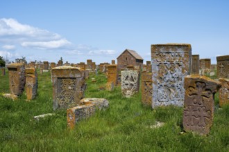 Ancient tombstones with carved patterns on an extensive green meadow, cross stones, khachkars,