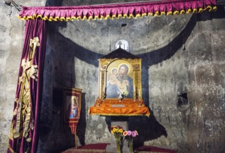 An altar with a religious icon surrounded by curtains and flowers in a decorated interior,